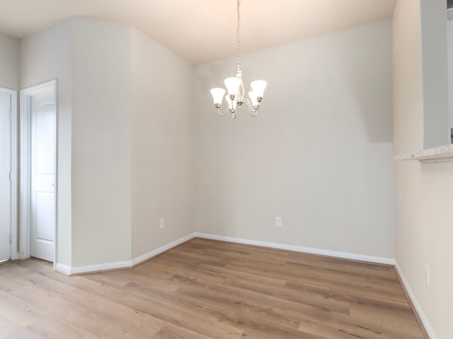 unfurnished room featuring light wood-type flooring and a notable chandelier