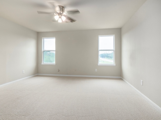 carpeted spare room with ceiling fan and plenty of natural light