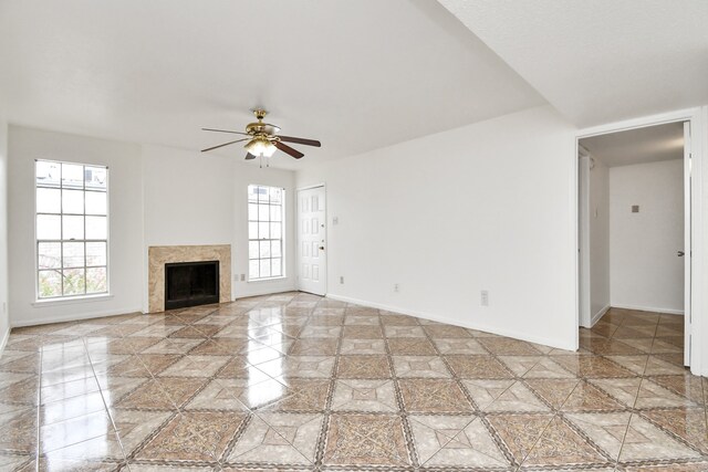 unfurnished living room featuring ceiling fan and a tiled fireplace