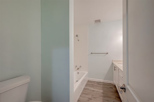 bathroom featuring vanity, hardwood / wood-style flooring, toilet, and a bath