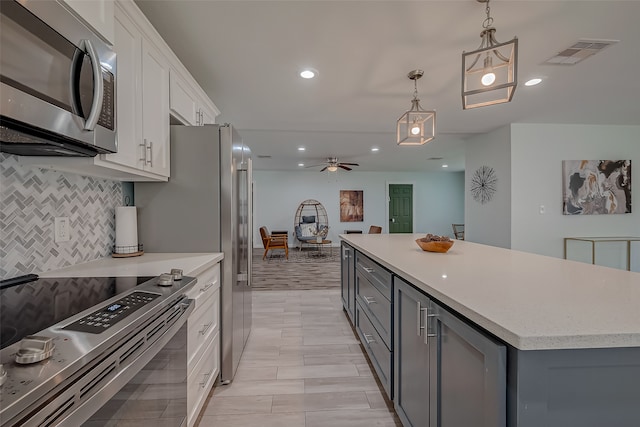 kitchen featuring gray cabinetry, white cabinetry, appliances with stainless steel finishes, pendant lighting, and a center island