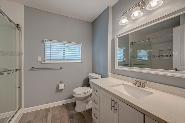 bathroom with hardwood / wood-style floors, vanity, toilet, and a shower with door