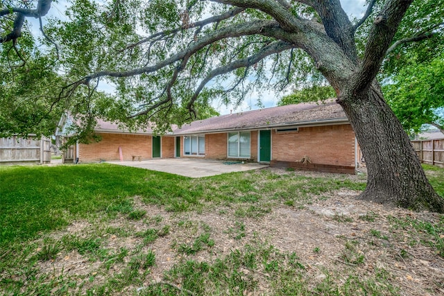 back of property with a lawn and a patio area