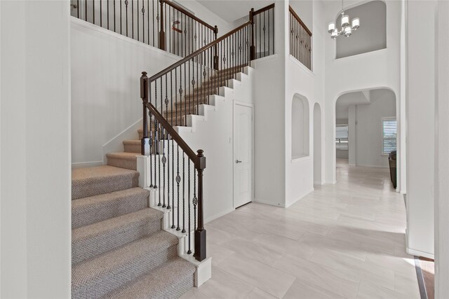 staircase with a high ceiling and an inviting chandelier