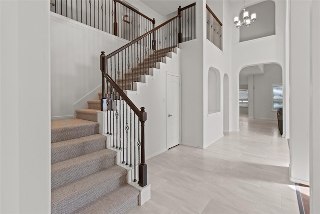 staircase with a high ceiling and an inviting chandelier