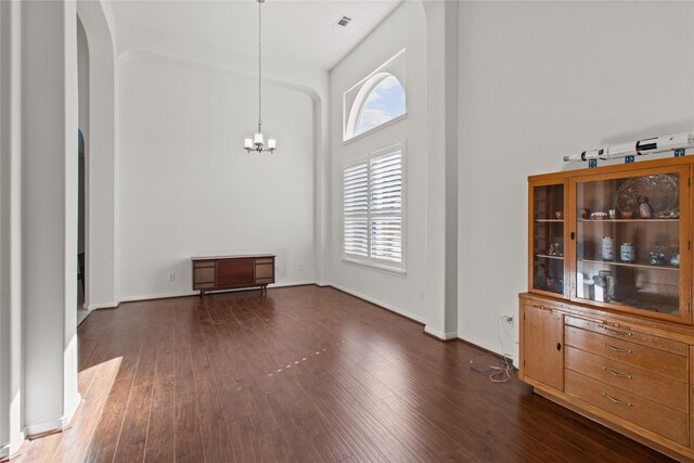 interior space with a towering ceiling, dark hardwood / wood-style floors, and a notable chandelier