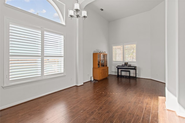 spare room with a high ceiling, dark hardwood / wood-style floors, and a notable chandelier