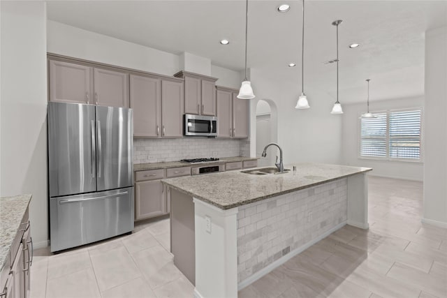 kitchen with decorative light fixtures, an island with sink, stainless steel appliances, and sink