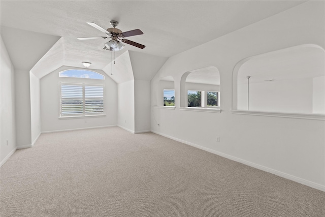 carpeted spare room featuring ceiling fan, plenty of natural light, vaulted ceiling, and a textured ceiling