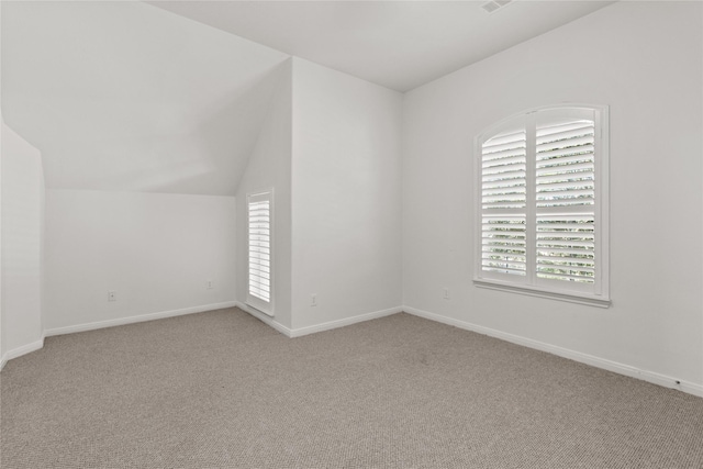 spare room featuring light colored carpet and vaulted ceiling