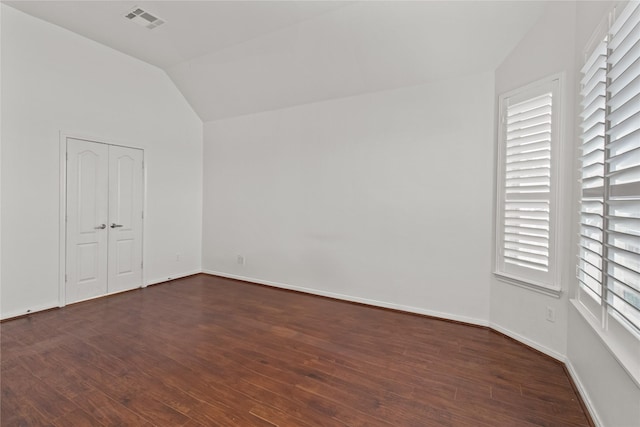 spare room with dark hardwood / wood-style floors and lofted ceiling