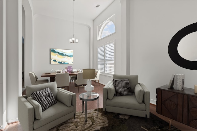 living room featuring hardwood / wood-style flooring, a towering ceiling, and an inviting chandelier