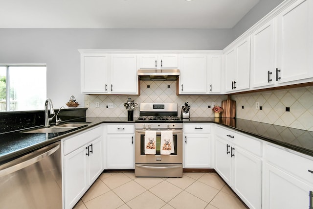 kitchen featuring tasteful backsplash, stainless steel appliances, sink, light tile patterned floors, and white cabinetry