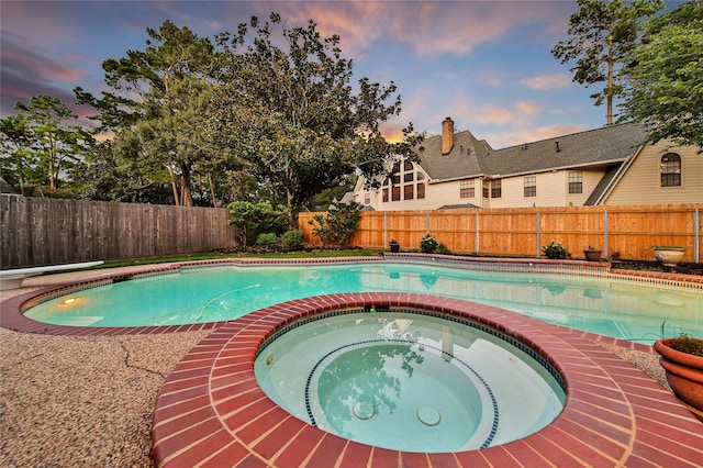 pool at dusk with an in ground hot tub