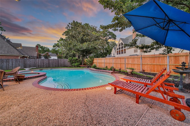 pool at dusk featuring an in ground hot tub and a patio area