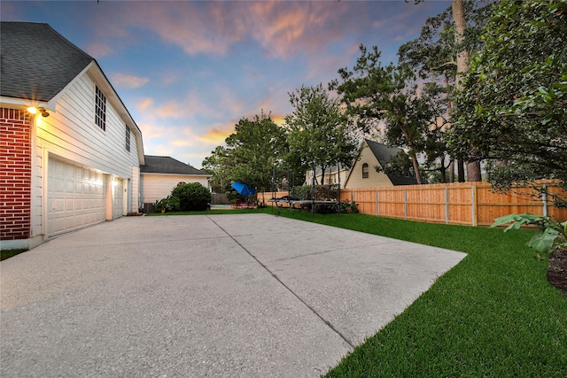 patio terrace at dusk with a lawn, central air condition unit, and a garage