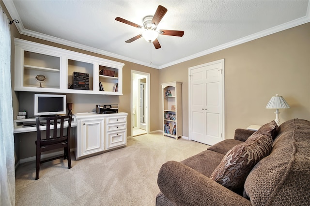 carpeted office space with ceiling fan, a textured ceiling, built in desk, and ornamental molding