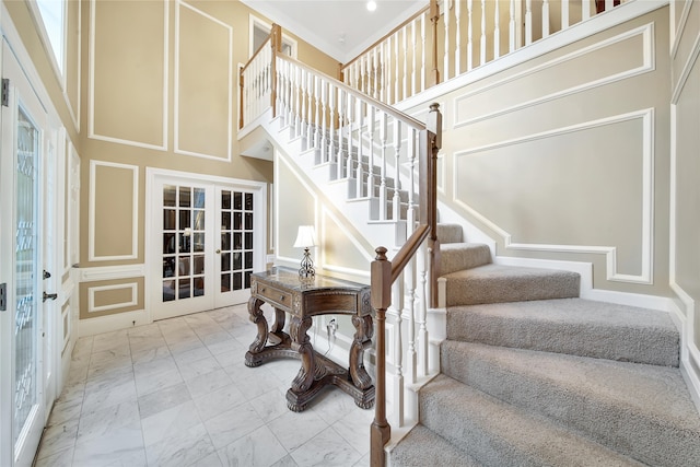 stairs with a high ceiling, french doors, and ornamental molding