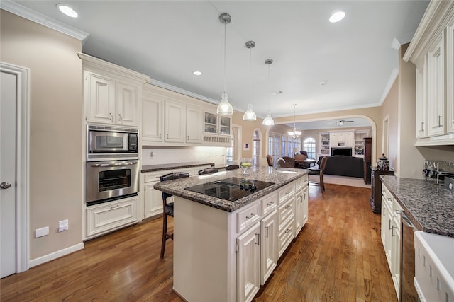 kitchen featuring stainless steel appliances, a kitchen island, hanging light fixtures, a breakfast bar area, and dark wood-type flooring