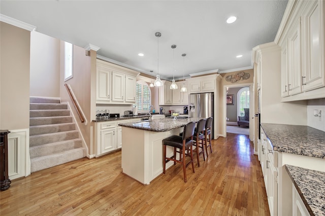 kitchen with a kitchen breakfast bar, plenty of natural light, light hardwood / wood-style flooring, and a kitchen island