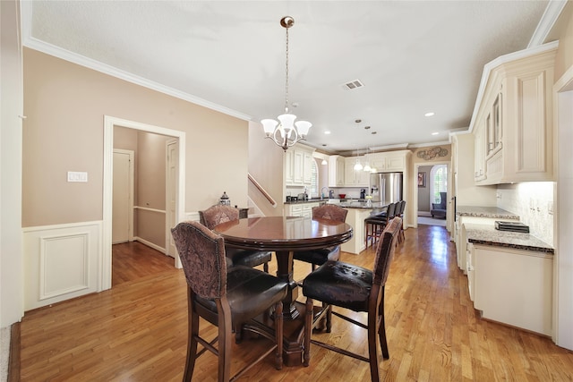 dining area featuring light hardwood / wood-style floors, a notable chandelier, sink, and crown molding