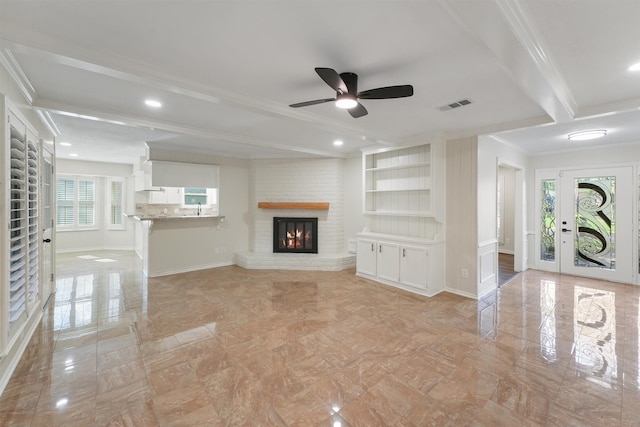 unfurnished living room with beam ceiling, ceiling fan, a healthy amount of sunlight, and a brick fireplace