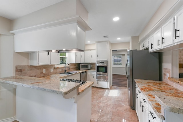 kitchen with white cabinets, light stone countertops, tasteful backsplash, kitchen peninsula, and stainless steel appliances