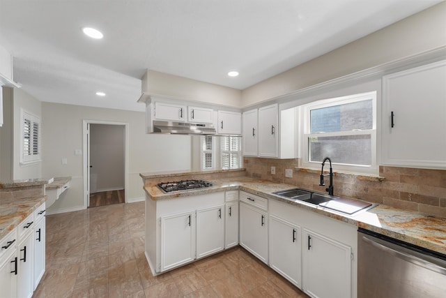 kitchen with sink, kitchen peninsula, decorative backsplash, white cabinets, and appliances with stainless steel finishes