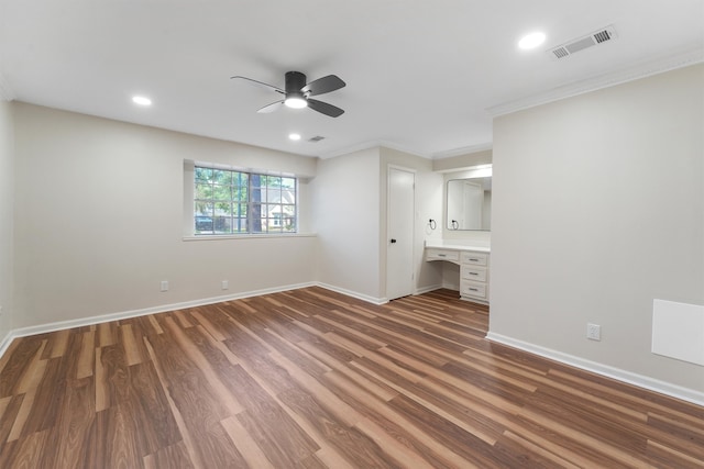 unfurnished bedroom with ensuite bath, ceiling fan, dark wood-type flooring, and ornamental molding