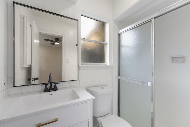 bathroom with an enclosed shower, vanity, ceiling fan, tile walls, and toilet