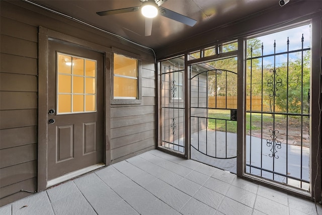 entryway featuring ceiling fan and wood walls