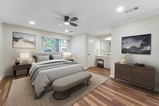 bedroom with ceiling fan, ensuite bathroom, wood-type flooring, and crown molding