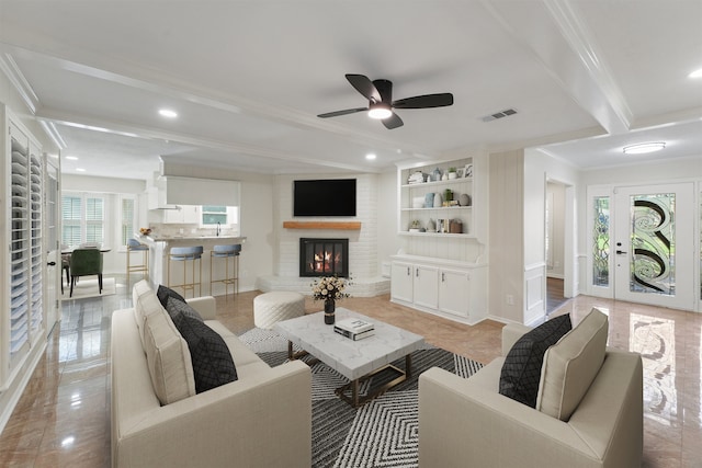 tiled living room featuring a fireplace, a wealth of natural light, ornamental molding, and ceiling fan