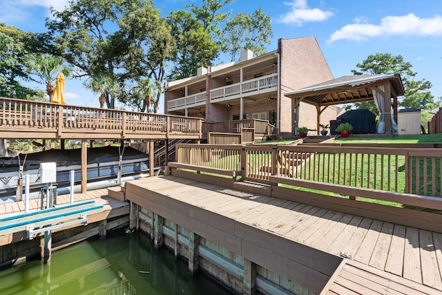 view of dock with a gazebo, a water view, and a yard