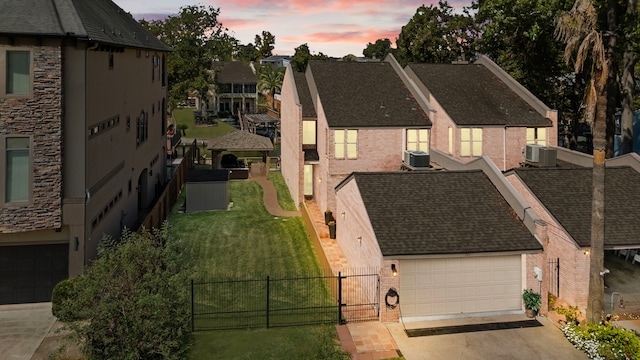 view of front of house with central AC, a yard, and a garage