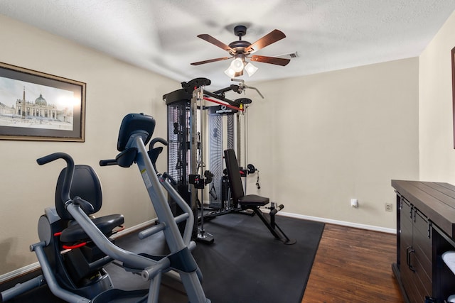 workout area with ceiling fan, a textured ceiling, and dark hardwood / wood-style flooring