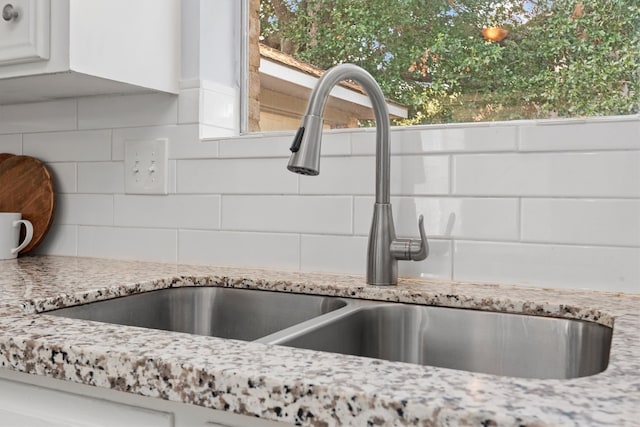 interior details with white cabinetry, sink, and tasteful backsplash