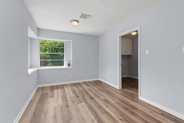 empty room featuring a textured ceiling and light hardwood / wood-style flooring