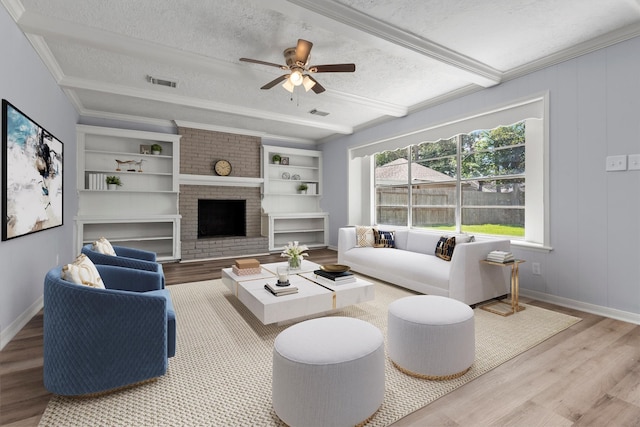 living room featuring hardwood / wood-style flooring, a fireplace, a textured ceiling, and crown molding