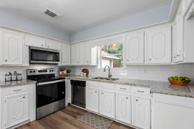 kitchen with stainless steel appliances, white cabinetry, sink, backsplash, and dark hardwood / wood-style flooring