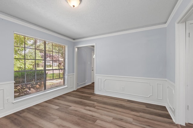 unfurnished room with a textured ceiling, hardwood / wood-style floors, and crown molding