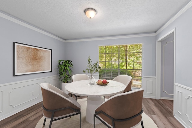 dining area featuring wood-type flooring, a textured ceiling, and crown molding