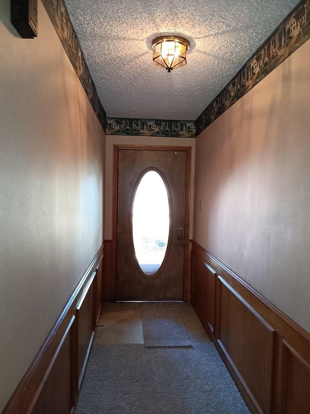 doorway with carpet flooring and a textured ceiling