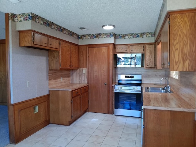 kitchen featuring decorative backsplash, appliances with stainless steel finishes, a textured ceiling, and sink