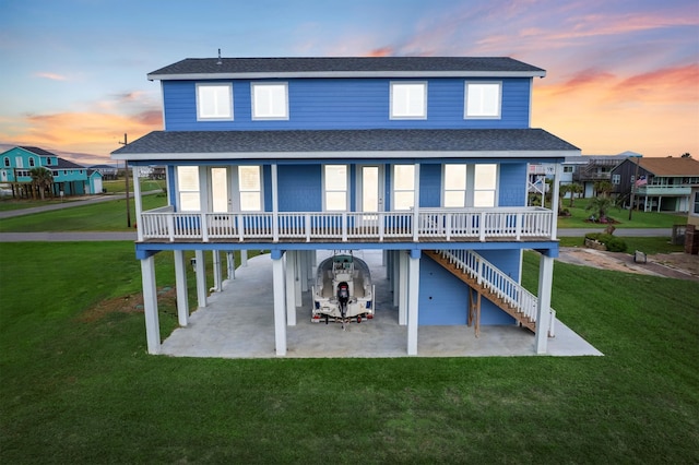 back house at dusk featuring a porch and a lawn