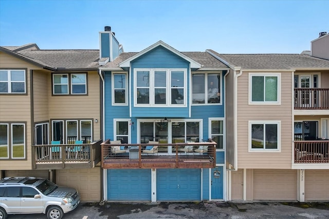 rear view of house featuring a garage and a balcony