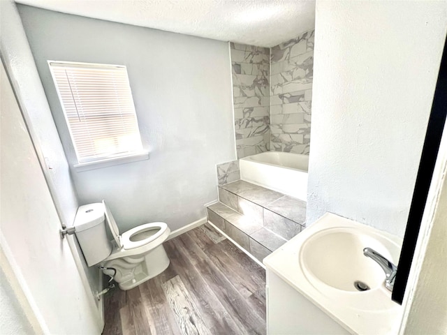 bathroom featuring vanity, wood-type flooring, a textured ceiling, and toilet