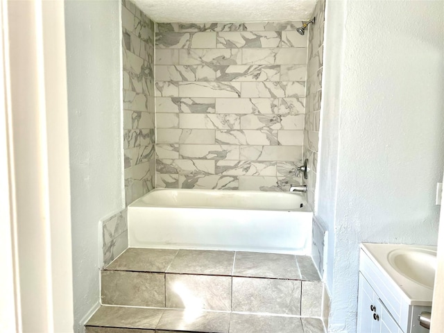 bathroom featuring vanity, a textured ceiling, and tiled shower / bath