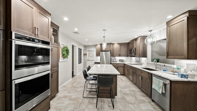 kitchen with sink, appliances with stainless steel finishes, decorative backsplash, and a center island