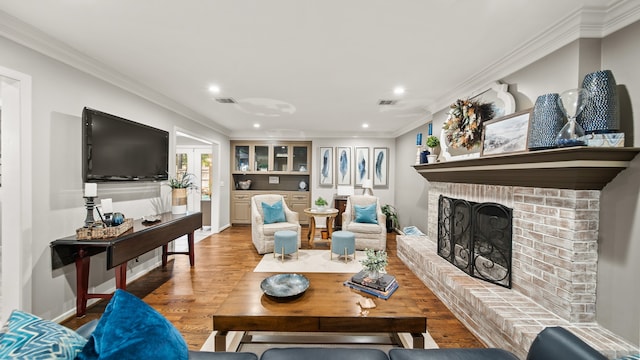 living room featuring hardwood / wood-style floors, ornamental molding, and a brick fireplace